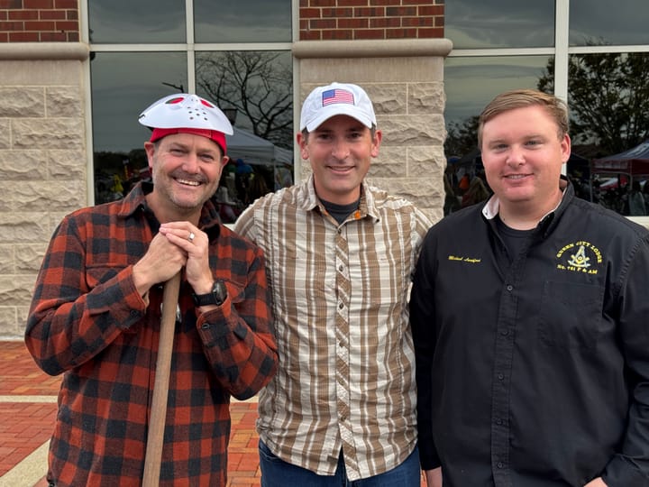 Three attendees posing outside a brick and stone building