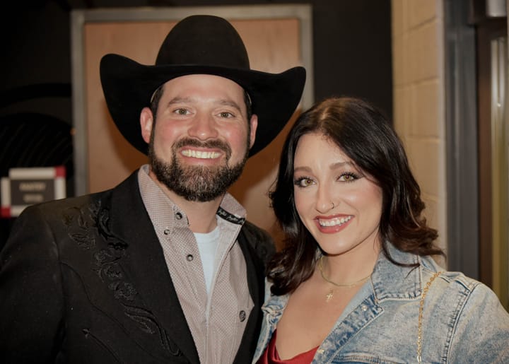 Two smiling guests, one in a black cowboy hat and one in denim