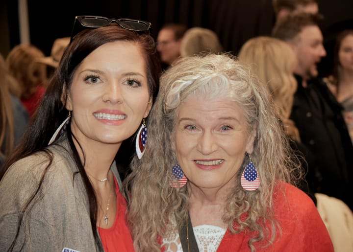 Two smiling guests, one wearing flag-patterned earrings