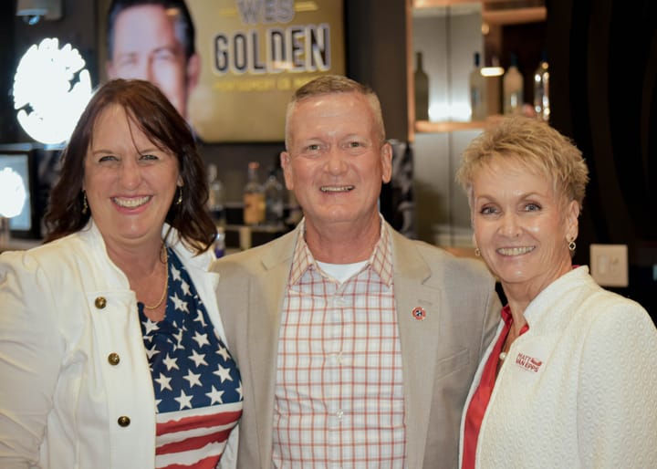 Three smiling guests posing near the event entrance