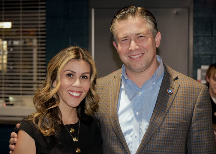Two guests posing in a black top and checked blazer