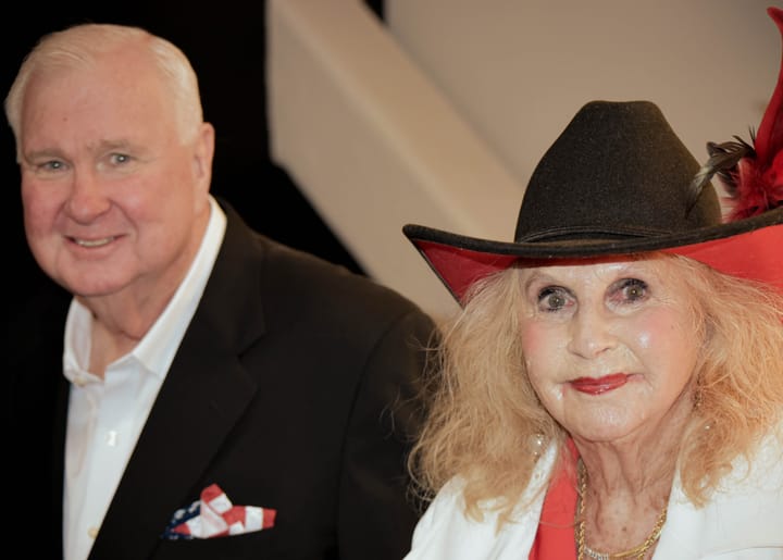 Two guests posing, one wearing a decorated black cowboy hat