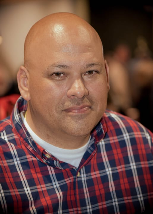 A seated guest wearing a red and blue plaid shirt