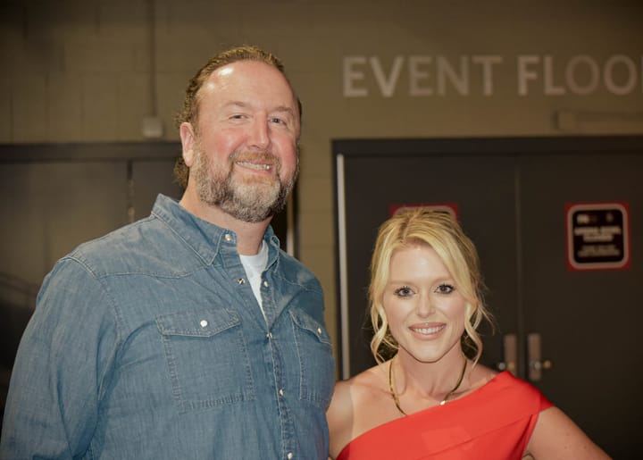 Two smiling guests posing in blue and red clothing