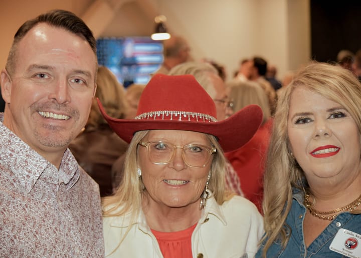 Three guests posing together, with a red cowboy hat in the center