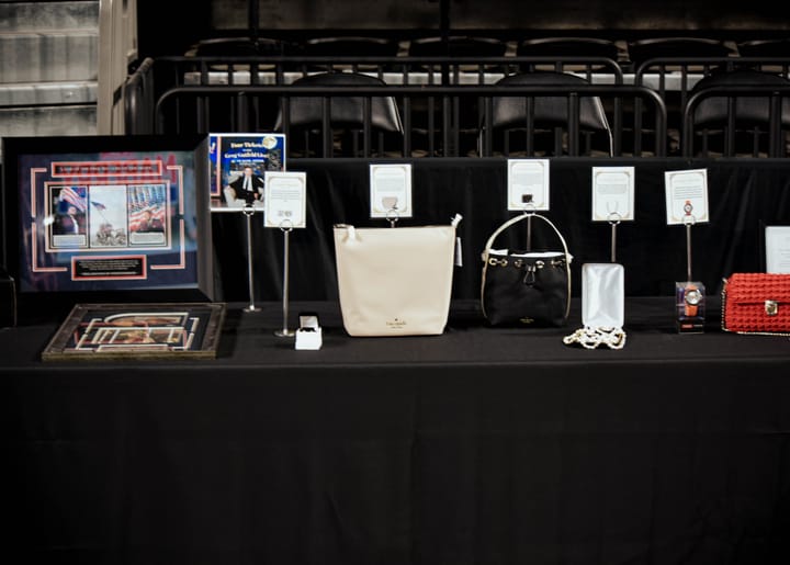 Handbags and framed items displayed on the silent auction table