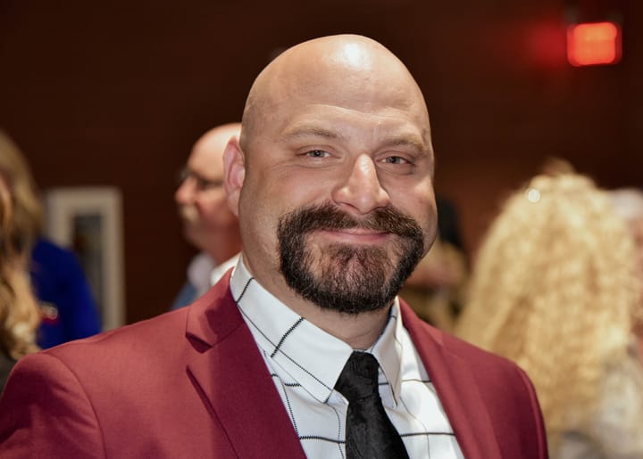 A smiling guest wearing a burgundy blazer and dark tie