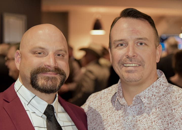 Two guests posing in a burgundy blazer and patterned shirt
