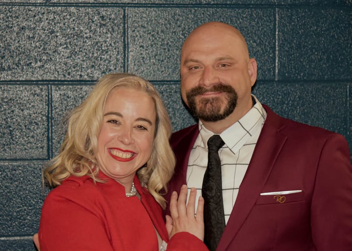 Two smiling guests wearing red and burgundy jackets