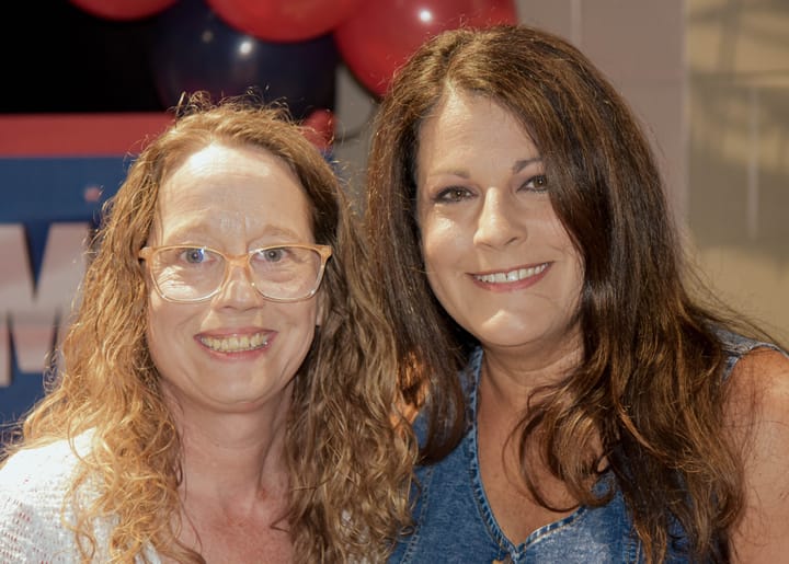Two guests smiling together beside the balloon decorations