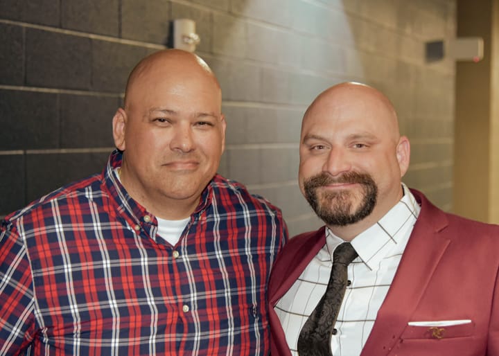 Two guests posing in a plaid shirt and burgundy blazer