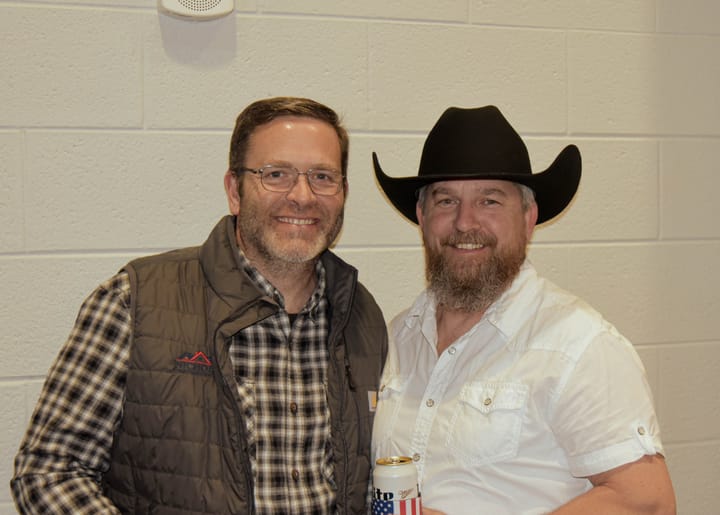 Two smiling guests, one wearing a black cowboy hat and white shirt