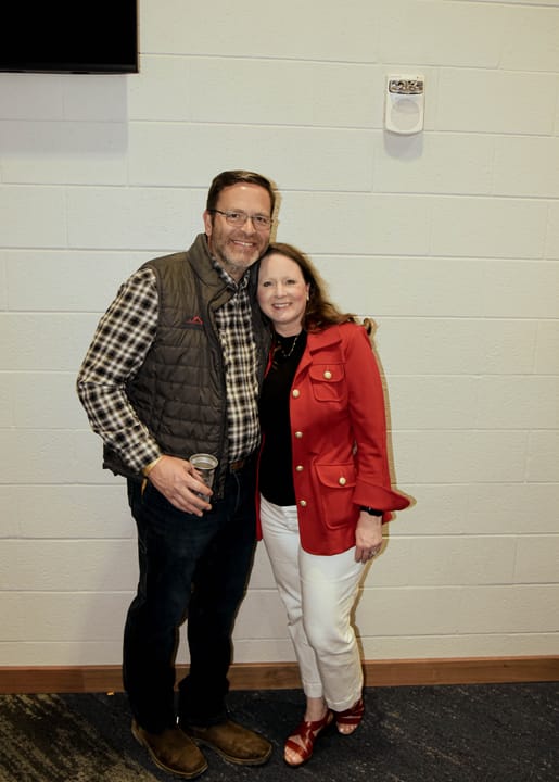 Two guests standing together against a light-colored wall