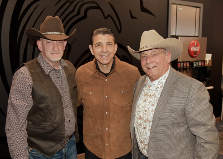 Three smiling guests, with cowboy hats on either side