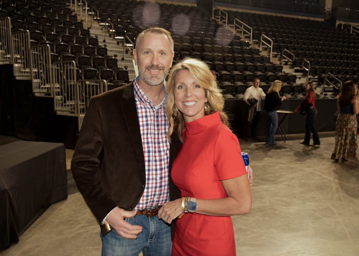 Two guests posing together with arena seating behind them