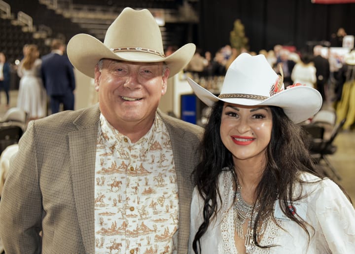 Two smiling guests wearing light-colored cowboy hats