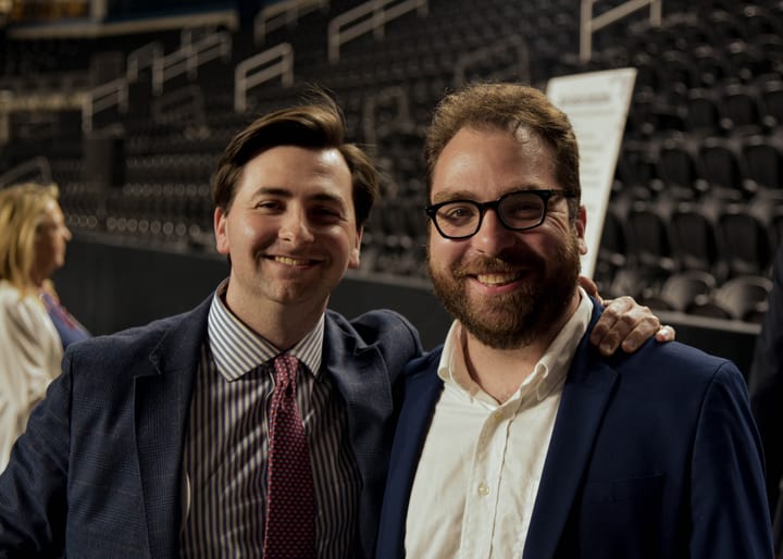 Two smiling guests wearing dark suits