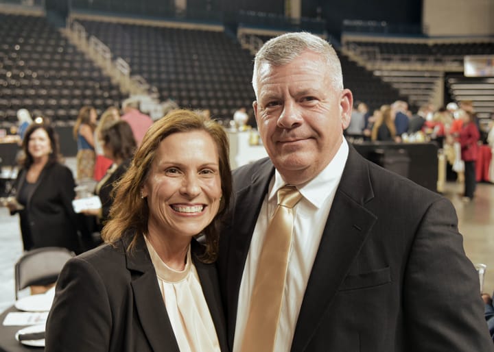 Two guests posing together in dark jackets and light shirts