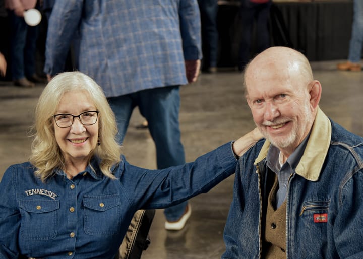 Two seated guests smiling together in denim jackets