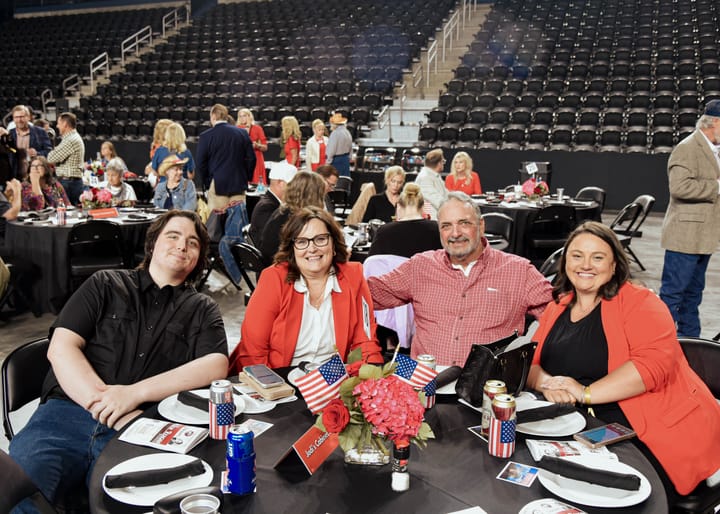Four guests posing around a dinner table with a floral centerpiece