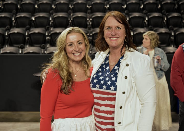 Two smiling guests, one in a red top and one in a flag-patterned dress
