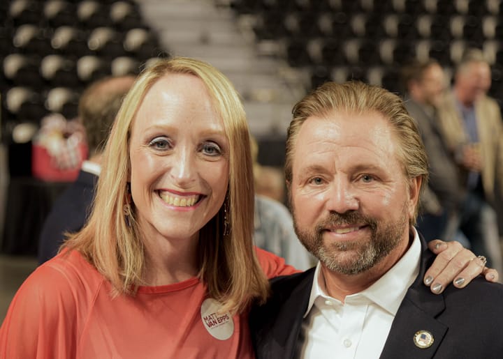 Two smiling guests in a red top and dark blazer