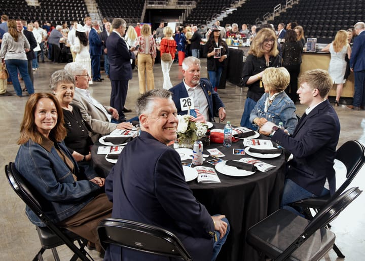 Guests smiling around a dinner table on the arena floor