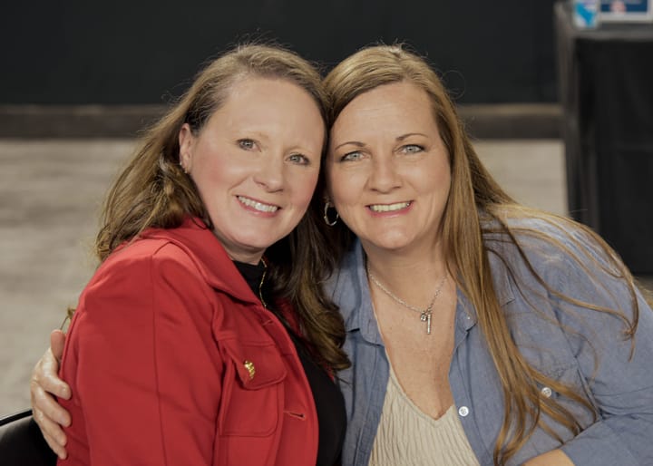 Two guests smiling together in red and blue jackets