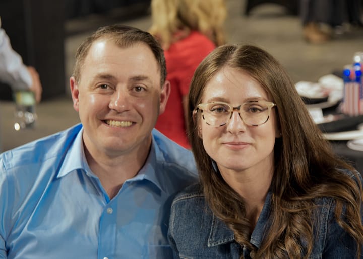 Two seated guests posing in a light blue shirt and denim jacket