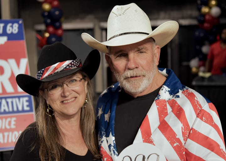 Two guests in cowboy hats, one wearing a flag-patterned jacket