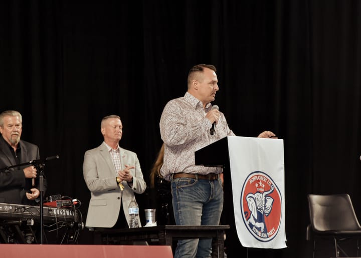 A speaker holding a microphone at the party lectern