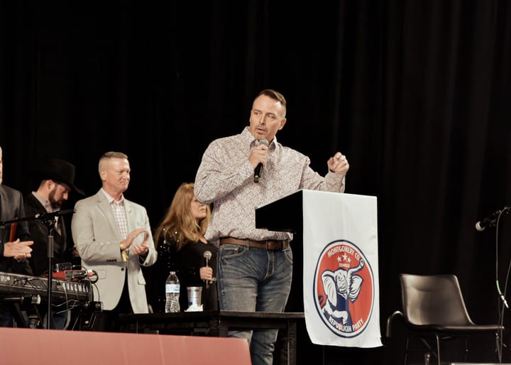 A speaker gesturing with one hand while holding a microphone