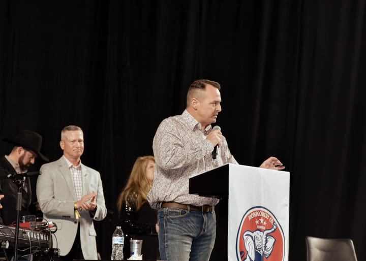 A speaker in a patterned shirt speaking at the lectern