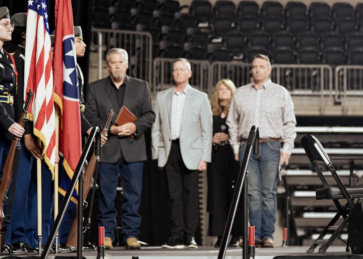 Flag bearers and guests standing on stage beside the American and Tennessee flags