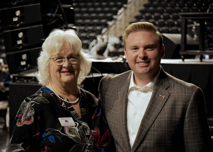 Two smiling guests posing together near the stage