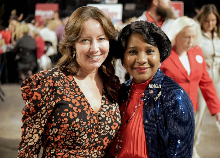 Two guests smiling in a floral dress and blue sequined jacket