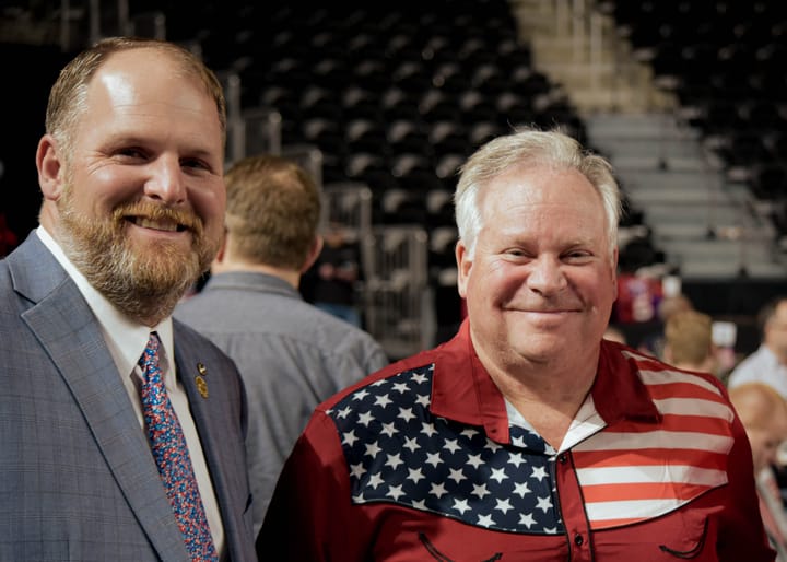 Two guests posing in a suit and a flag-patterned shirt