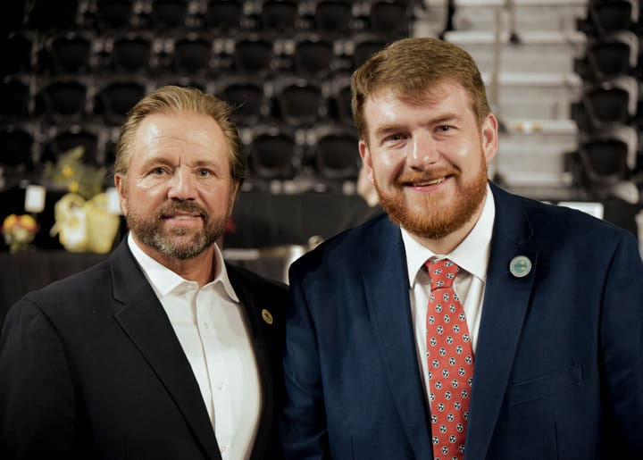 Two smiling guests posing together in dark suits