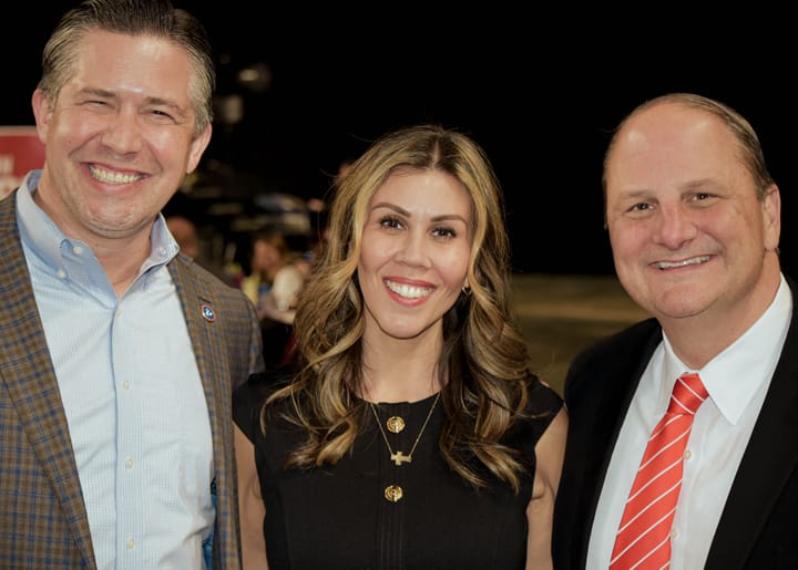 Three smiling guests posing together, with a black dress in the center