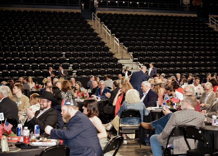 Guests seated at dinner tables beneath the arena stands
