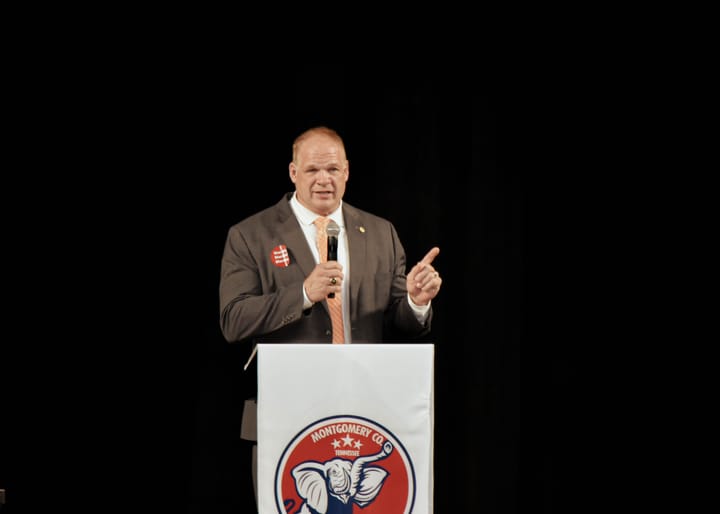 A wide view of a speaker gesturing behind the party lectern