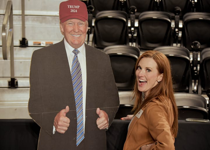A smiling guest posing beside a cardboard figure in the arena