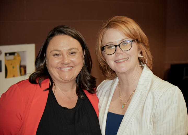 Two smiling guests posing in red and white jackets