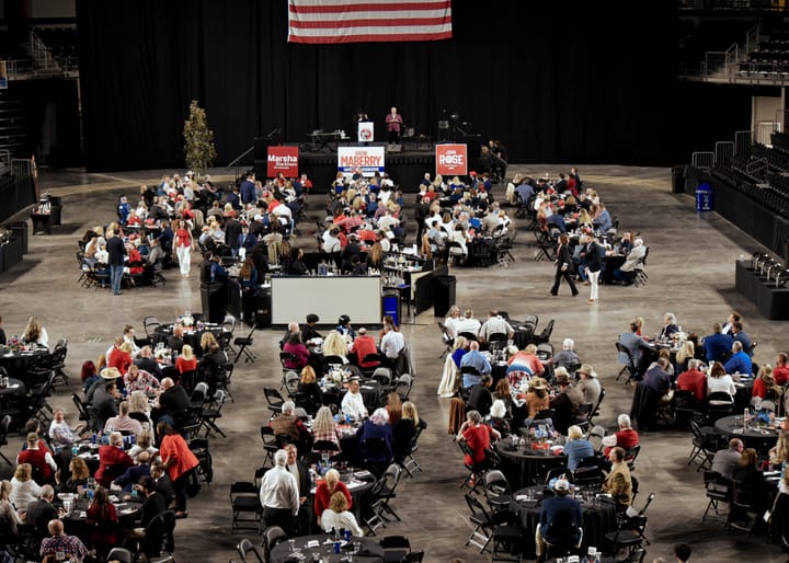 An elevated view of the dinner tables and stage beneath an American flag