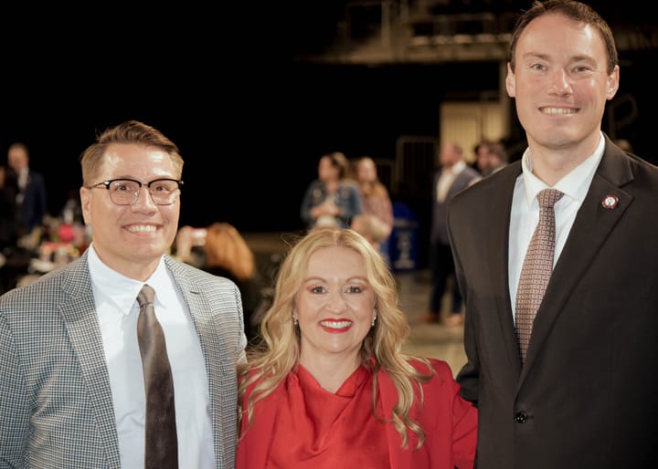 Three guests posing together, with a red jacket in the center