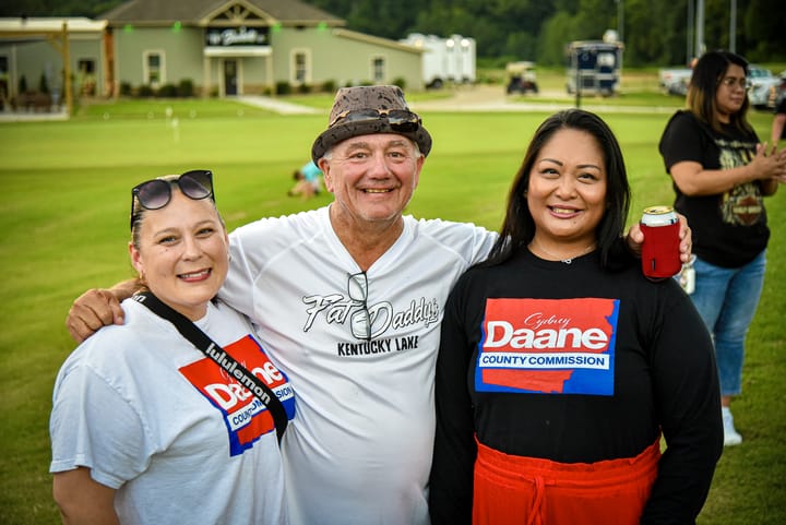 Three guests smiling together on the lawn
