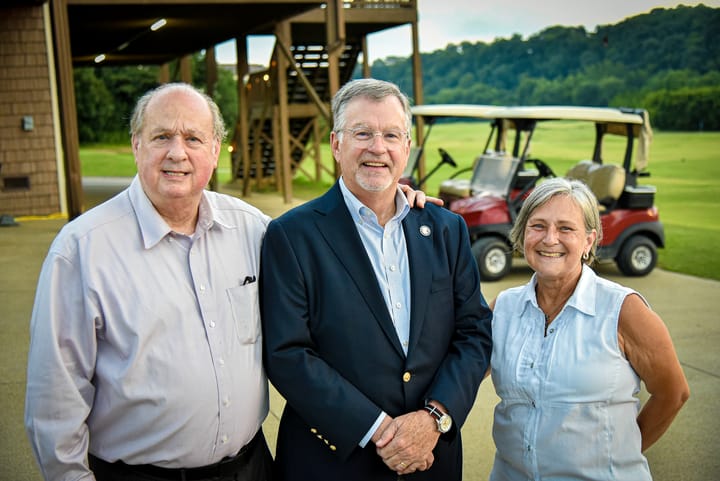 Three guests posing beside a golf cart