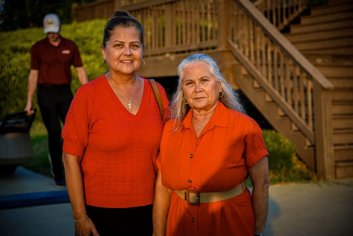 Two guests in red posing beside the wooden stairs