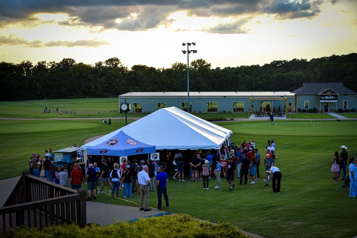 A wide view of guests gathered around the event tents