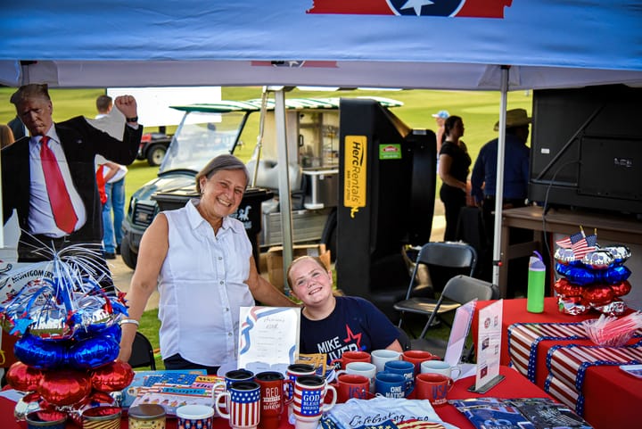 Two guests behind a table of patriotic merchandise